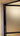 Close-up of a frosted glass hinged door with black metal frame inside a beige wall frame