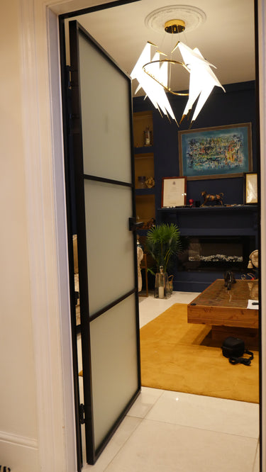 Modern interior with frosted glass hinged door, blue wall, yellow rug, wooden coffee table, and chandelier
