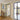 Open black framed glass hinged door in modern interior with beige walls and wooden floor