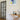 Modern interior with black framed glass hinged door, wooden console table, abstract wall art, and decorative sculptures