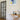 Modern interior with black framed glass hinged door, wooden console table, abstract wall art, and decorative sculptures