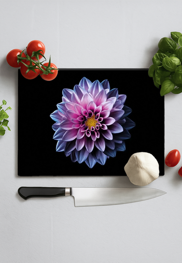Black chopping board with large purple dahlia print surrounded by tomatoes, garlic, basil, and chef knife on white surface