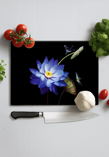 Black chopping board with blue lotus flower and dragonfly design surrounded by tomatoes, garlic, basil, herb, and knife