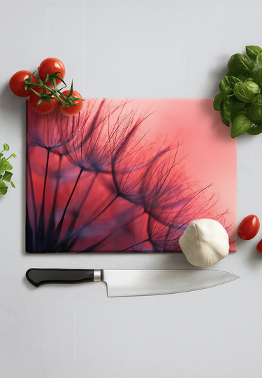 Red dandelion printed glass chopping board with knife, garlic, cherry tomatoes, and basil leaves