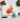Glass chopping board with a red flower illustration, surrounded by tomatoes, garlic, basil, and a kitchen knife