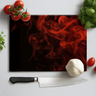 Rectangular black chopping board with red smoke design, surrounded by tomatoes, basil, garlic, and knife