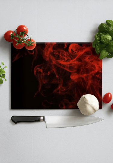 Rectangular black chopping board with red smoke design, surrounded by tomatoes, basil, garlic, and knife
