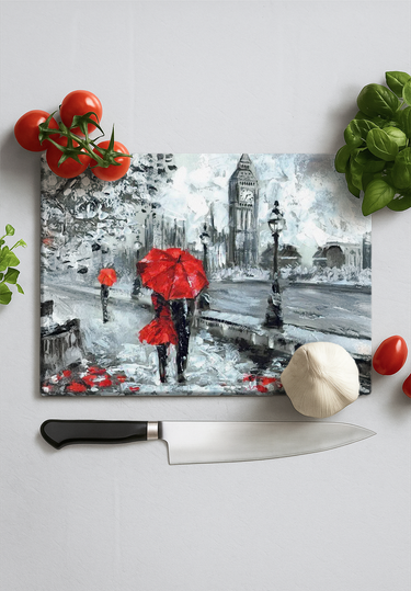 London-themed chopping board with red umbrellas art, fresh tomatoes, basil, garlic, and chef knife on white surface