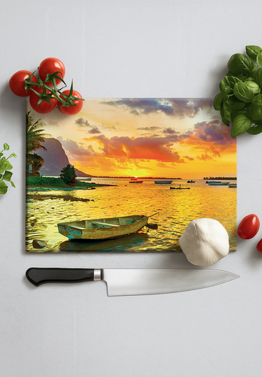 Chopping board with sunset seascape featuring small boat, tomatoes, basil, garlic, and kitchen knife