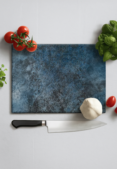 Textured blue chopping board with a chef knife, garlic bulb, fresh tomatoes and basil leaves on white surface