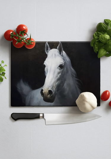 Rectangular chopping board with white horse painting surrounded by cherry tomatoes, basil, garlic, and kitchen knife