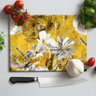 Floral decorative cutting board with tomatoes, basil, garlic, and chef knife on white surface