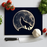 Kitchen chopping board with wolf silhouette howling at full moon design, surrounded by tomatoes, garlic, basil, and knife