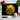 Black chopping board with vibrant yellow and red dahlia print surrounded by cherry tomatoes, garlic, basil, and chef knife