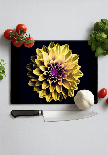 Black chopping board with yellow and purple dahlia design, kitchen knife, garlic, tomatoes, and herbs