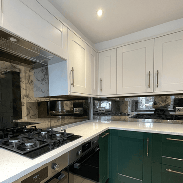 Modern kitchen with white and green cabinets, marble backsplash, and glass splashback