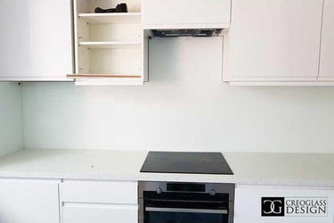 Modern kitchen with sleek white cabinets, built-in oven, and minimalist countertop design
