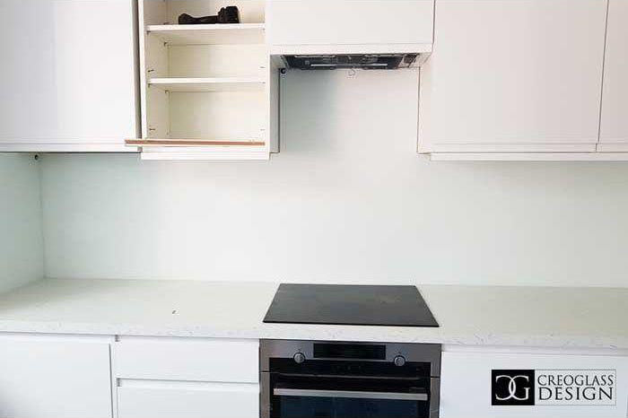 Modern kitchen with sleek white cabinets, built-in oven, and minimalist countertop design