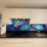 Vibrant blue and gold abstract glass splashback in modern kitchen with white cabinets and black countertop
