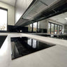 Modern kitchen with sleek black glass cooktop and marble countertops, featuring luxury architectural glass design