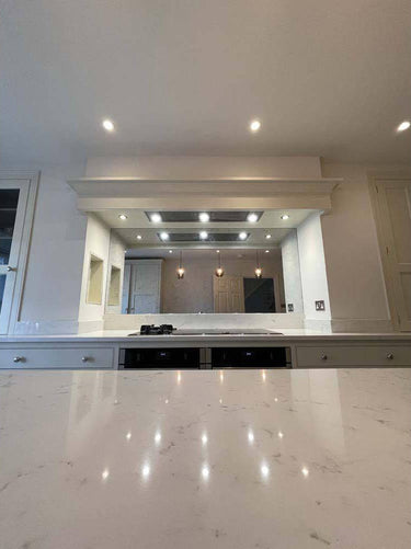 Bespoke feature mirror above kitchen island, reflecting luxury residential interior with recessed lighting