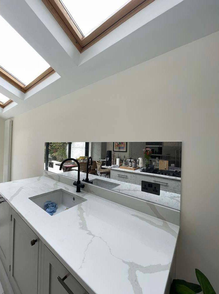 Bespoke feature mirror above marble kitchen sink with skylights, modern luxury residential design