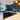 Vibrant underwater scene on custom glass kitchen backsplash with dark cabinets and pendant lights