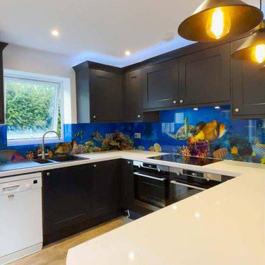 Vibrant underwater scene on custom glass kitchen backsplash with dark cabinets and pendant lights