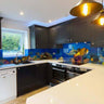 Vibrant underwater scene on custom glass kitchen backsplash with dark cabinets and pendant lights