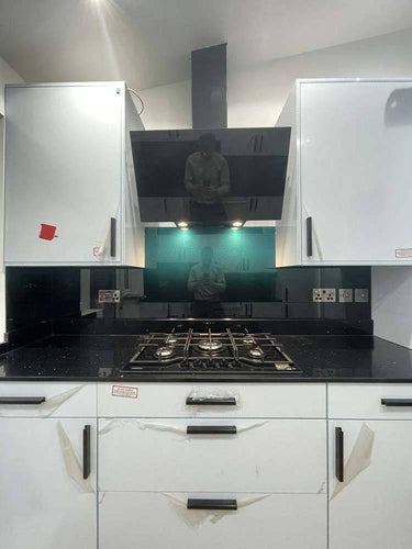 Modern kitchen with black glass backsplash and LED-lit feature panel above gas hob