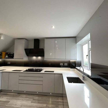 Modern kitchen with sleek white cabinets, black glass backsplash, and integrated lighting for luxury residential design