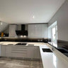 Modern kitchen with sleek white cabinets, black glass backsplash, and integrated lighting for luxury residential design