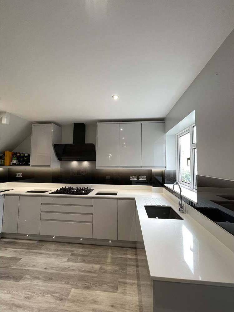 Modern kitchen with sleek white cabinets, black glass backsplash, and integrated lighting for luxury residential design