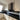 Modern kitchen with black glass splashback and white cabinets, featuring sleek design and contemporary style.