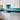 Modern kitchen with turquoise glass splashback, white cabinets, and grey countertop