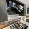 Luxury kitchen with bespoke glass splashback featuring marble veining and gold accents, modern gas hob