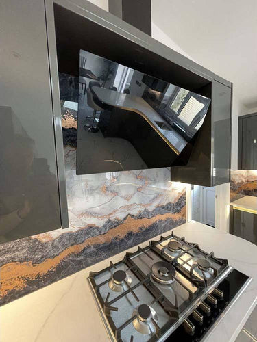 Luxury kitchen with bespoke glass splashback featuring marble veining and gold accents, modern gas hob