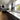 Modern kitchen with sleek black cabinets, white countertop, and decorative glass backsplash featuring abstract wave design.