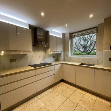 Modern kitchen with sleek white cabinets, marble-effect glass backsplash, and LED lighting accents
