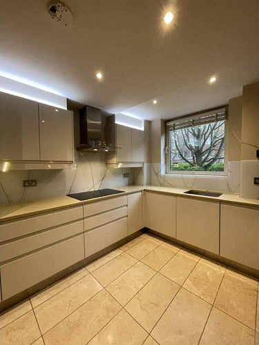 Modern kitchen with sleek white cabinets, marble-effect glass backsplash, and LED lighting accents