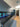 Modern kitchen with LED backlit glass splashback featuring blue floral design, sleek grey cabinets and black countertop.