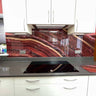 Bespoke red marble-effect glass kitchen splashback with modern white cabinets and black countertop