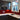 Vibrant red glass kitchen splashback with sleek black cabinets and white countertop