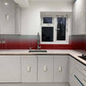 Modern kitchen with red gradient glass splashback, sleek grey cabinets, and white countertop