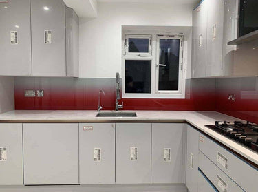 Modern kitchen with red gradient glass splashback, sleek grey cabinets, and white countertop