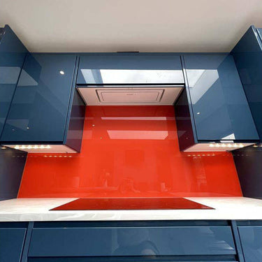 Vibrant red glass kitchen splashback with glossy blue cabinets and under-cabinet lighting