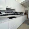 Modern kitchen with bespoke glass splashback featuring mountain wave design, sleek white cabinets, and granite countertop.