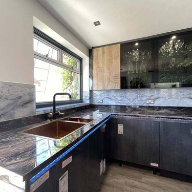 Modern kitchen with black marble countertop, LED-lit glass backsplash, and sleek cabinets