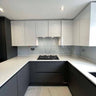 Modern kitchen with sleek white cabinets, grey marble backsplash, and glossy black lower units