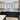 Modern kitchen with sleek black cabinets, white marble floor, and glass backsplash